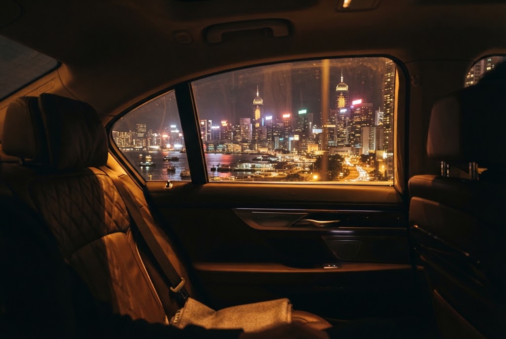 Blick vom Fondsitz einer Limousine auf eine beleuchtete Stadt bei Nacht