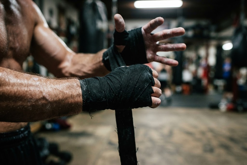 Hände werden vor dem Training mit schwarzen Boxbandagen gewickelt